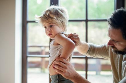 adult checking child's back for rash