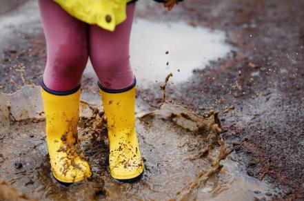 Child's rainboots jumping in a puddle