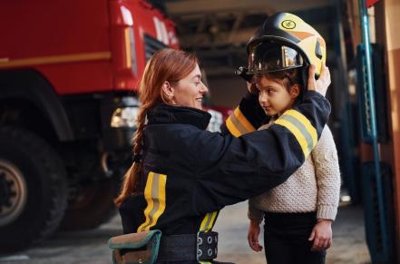 Firefighter putting helmet on child's head at fire station