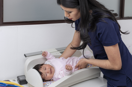 Doctor weighing a baby in office