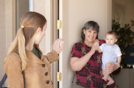 parent waving goodbye to child while in the arms of a child care provider