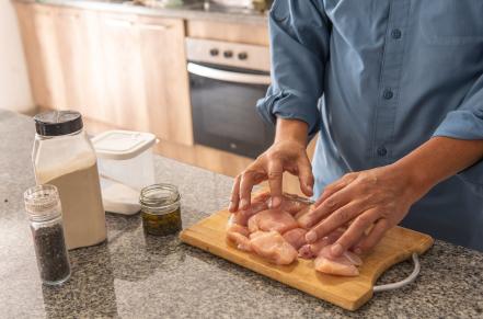 person preparing raw chicken on a cutting board