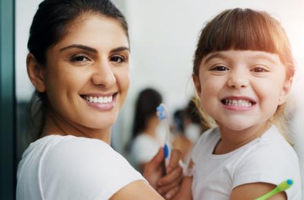 Adult and child brushing teeth together