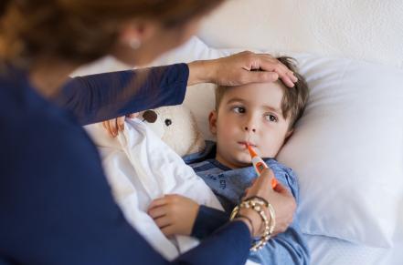 Child in bed having temperature taken