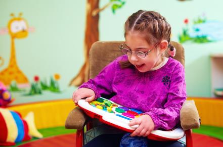 Child with special needs sitting in wheelchair playing with toy