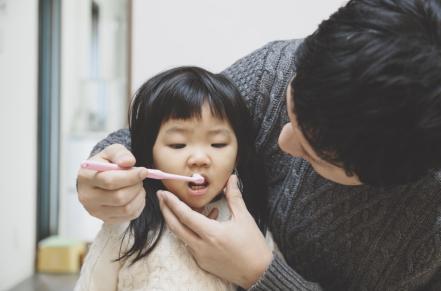 adult brushing child's teeth