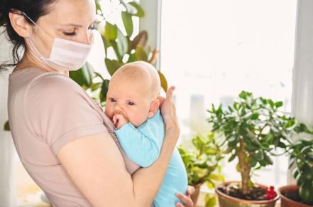 Masked adult holding sick infant