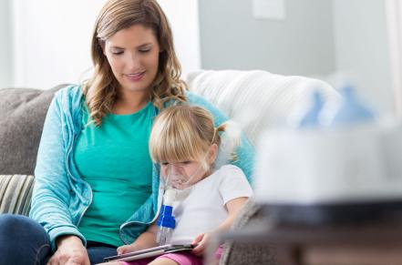 Adult sitting with child wearing an asthma nebulizer