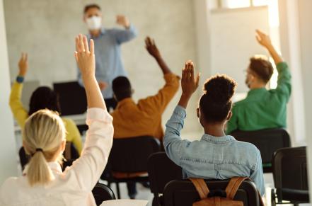 students raising hands in a class