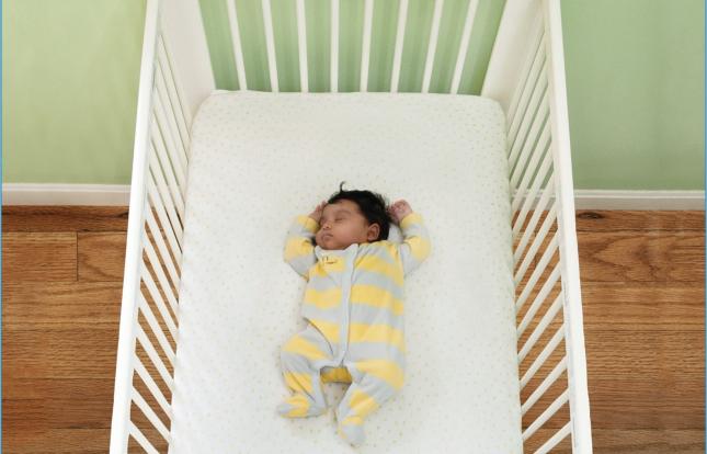 Infant sleeping on their back in a crib with no other items in crib