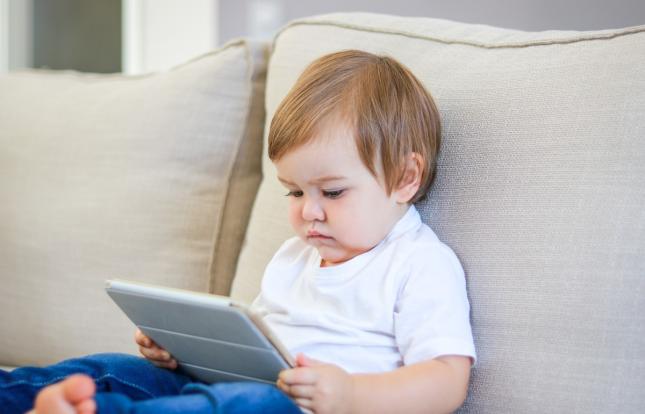 Toddler staring at a tablet screen