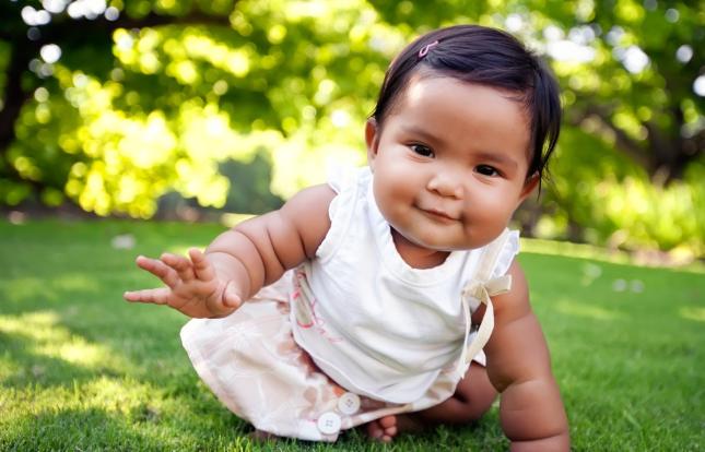 Baby crawling on grass looking proud