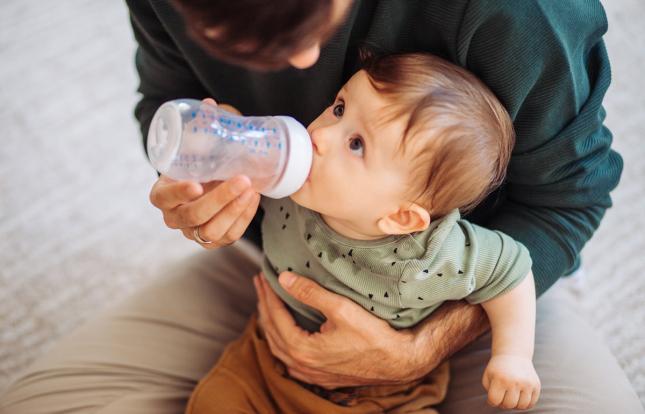 Adult feeding baby with a bottle