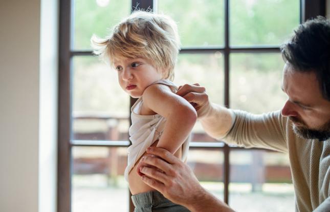 adult checking child's back for rash