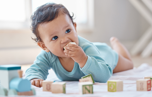 Baby on tummy teething on block