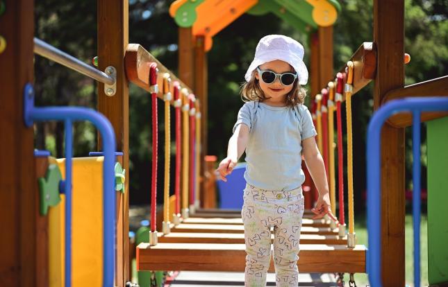 Child in hat and sunglasses on play structure