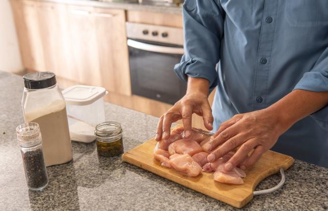 person preparing raw chicken on a cutting board