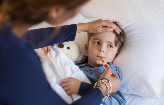 Child in bed having temperature taken