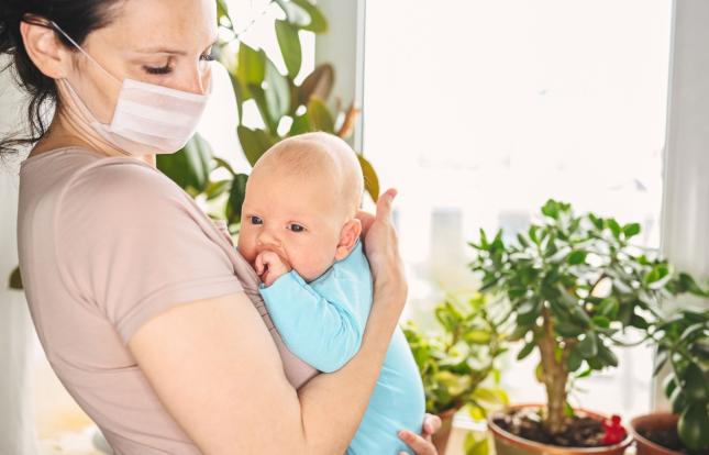 Masked adult holding sick infant